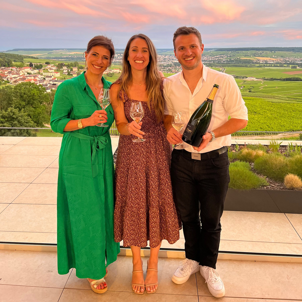 Three people standing together with drinks against a scenic background - Champagne D. Massin Producer's Club Shipment